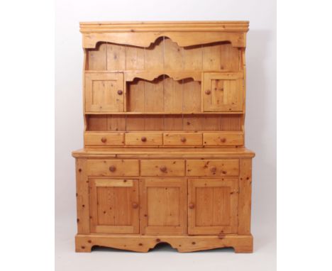A Continental pine dresser - late 20th century, the back with a deep reeded cornice over a shaped frieze, two small cupboards