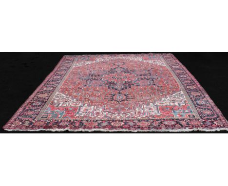 A Persian Heriz carpet - second half 20th century, the central red, dark-blue, pink, mid-blue and ivory eight-point medallion