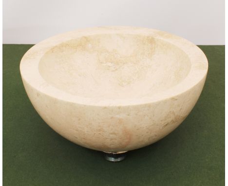 A modern natural stone circular wash-basin or sink - probably Travertine stone, mottled cream stone with a stainless steel pl