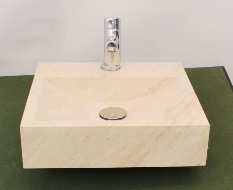 A modern natural stone wash basin or sink - probably Travertine stone, mottled cream stone with a chrome plated mixer tap and