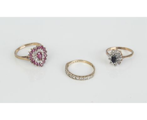Three 9ct yellow gold rings - comprising a white sapphire half eternity ring, size N; a ruby and diamond heart-shaped cluster