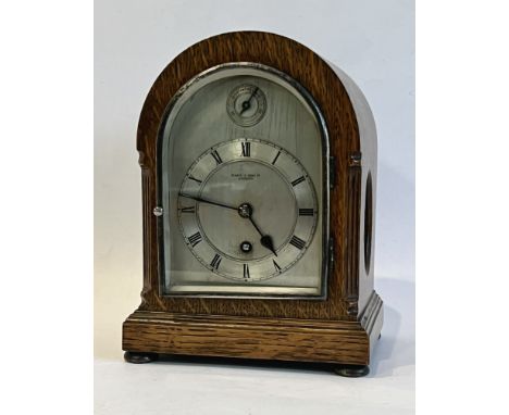 An oak 8 day mantel clock by Pearce &amp; Sons Ltd of Leicester - 1920s, with silvered arched dial with Roman chapter ring an