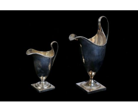 Two Edward VII silver cream jugs, both helmet shaped on square bases, one dated Birmingham 1909, the smaller example dated Ch