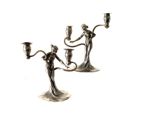 A pair of Art Nouveau figural candleholders by WMF, having a scantily clad young lady in flowing robe supporting a two branch