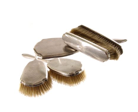 A George V silver dressing table set, the hand mirror, pair of hairbrushes and clothes brushes having engine turned backs (5)