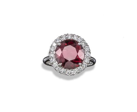 A garnet and diamond cluster ring, the circular-cut garnet set within a surround of round brilliant-cut diamonds in white gol
