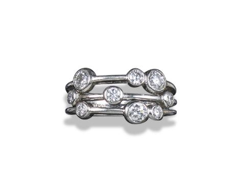 A diamond-set three-row platinum ring, set with graduated round brilliant-cut diamonds in platinum rubover-mounts, size M