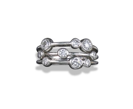 A diamond-set three-row platinum ring, set with graduated round brilliant-cut diamonds in platinum rubover-mounts, size M