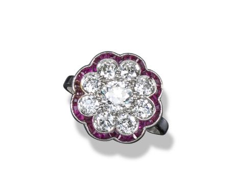 An Edwardian ruby and diamond cluster ring, the centre old circular-cut diamond is millegrain-set within a surround of eight 