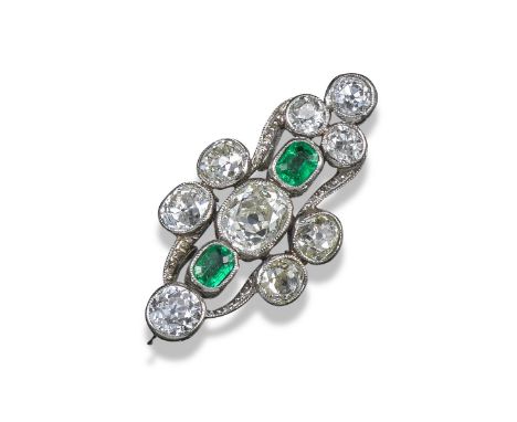 An early 20th century emerald and diamond scroll ring, set with nine graduated oval-shaped diamonds and two emerald-cut emera