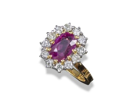 A ruby and diamond cluster ring, the oval-shaped ruby is set within a surround of twelve round brilliant-cut diamonds in yell