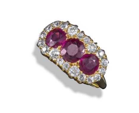 An early 20th century ruby and diamond ring, set with three graduated oval-shaped rubies within a border of circular-cut diam