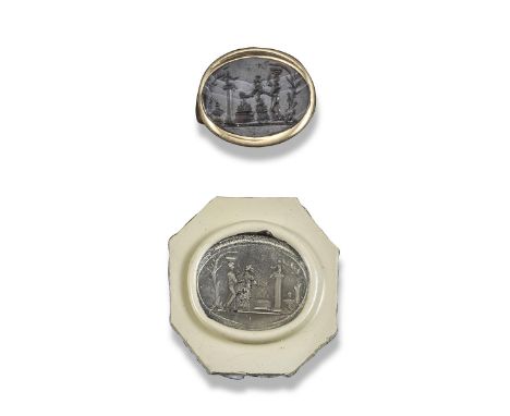A carved dark agate oval intaglio, possibly Babylonian, depicting an infant sitting on a pillar next to a fire and being atte
