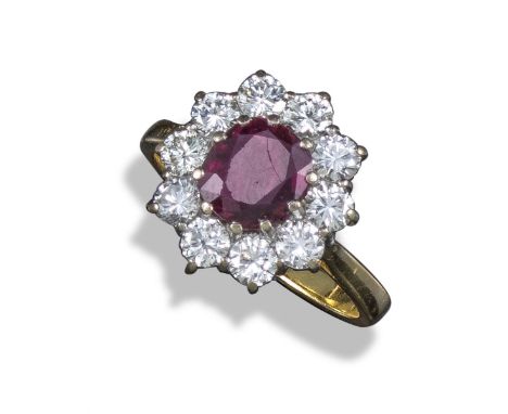 A ruby and diamond cluster ring, the slightly oval-shaped ruby set within a surround of ten round brilliant-cut diamonds in y