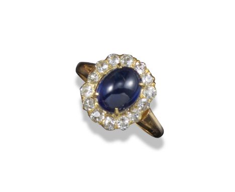 A sapphire and diamond cluster ring, the oval-shaped cabochon sapphire set within a surround of fourteen diamonds in yellow g