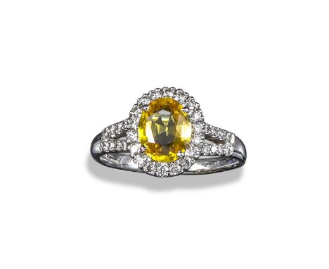 A yellow sapphire and diamond cluster ring, the oval-shaped sapphire set within a surround of round brilliant-cut diamonds in