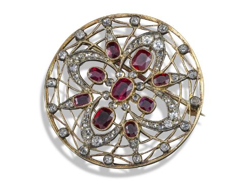 An Edwardian ruby and diamond brooch, of circular form and quatrefoil pierced and set with graduated oval-shaped rubies and d