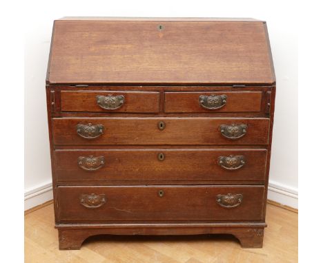 A late 18th century oak bureau, the fall front opening to fitted interior, over two short and three long graduated drawers wi