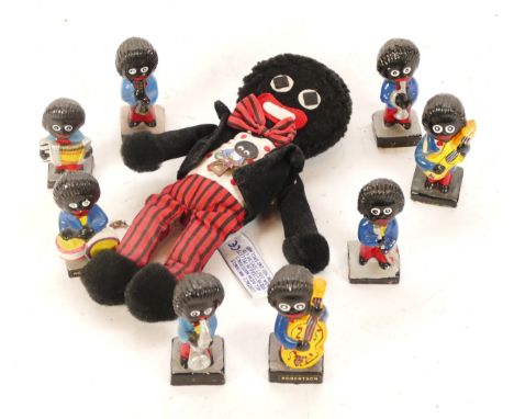 A set of eight mid 20th century Robertson's golly band playing figurines, together with a soft toy golly and an enamel badge.