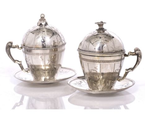 A pair of white metal continental covered cups with stands, 15.5cm