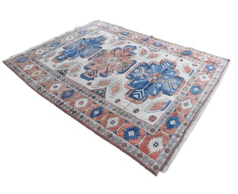 Large wool rug with three medallions in blue and red, repeating border, on cream ground, 300cm x 238cmMinor wear and possible