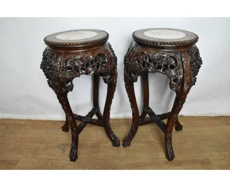 Pair of Chinese carved hardwood stands, each inset with circular marble panel, raised on carved cabriole legs united by X-sha