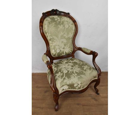 Victorian walnut open armchair, with upholstered pad back and seat in carved show wood frame on cabriole legs and castors