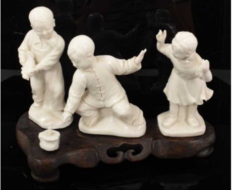 Chinese blanc de chine group of children playing, in the Cultural Revolution style, on wooden base measuring 21cm acrossSmall
