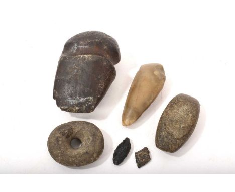 A group of early stone tools, probably North American, including a large grooved axe head, a doughnut-shaped stone, two small