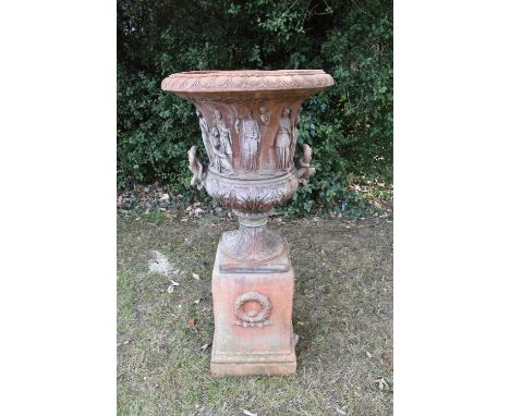 Large terracotta-style garden urn on plinth, of classical campana form, moulded with figures and leaves, raised on square pli