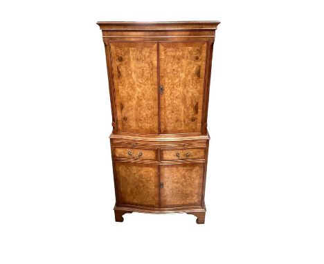 1950s walnut veneered cocktail cabinet, enclosed by a pair of serpentine front doors above a slide, two short drawers and cup