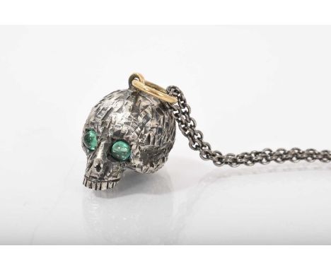 Silver novelty pendant in the form of a skull with two emerald cabochon eyes and gold suspension ring on a silver chain, Lond