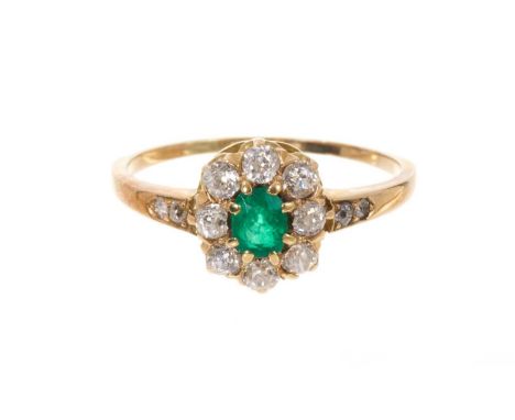 Emerald and diamond cluster ring with an oval mixed cut emerald surrounded by eight old cut diamonds in claw setting with dia