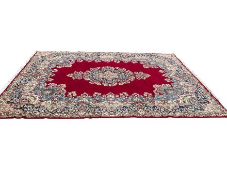 Large Kirnan carpet, with central medallion on claret field within main foliage border with tassel ends, approximately 400 x 