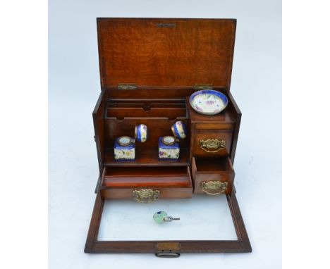 A Victorian oak stationery case with hinged top and glazed fall front, fitted with rack, drawer, ceramic ink bottles and bowl