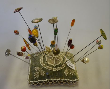 A beaded velvet pin cushion, holding a collection of hat-pins, including glass, enamel and gilt metal examples