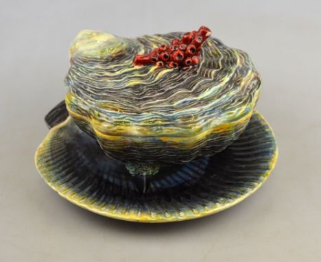A majolica bowl and cover in the form of an oyster shell with a coral finial raised on three mussel shell feet to/w a matchin
