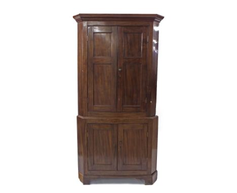 Mahogany corner cupboard, the moulded cornice over twin blind panelled doors enclosing a shelved interior, over a base cupboa