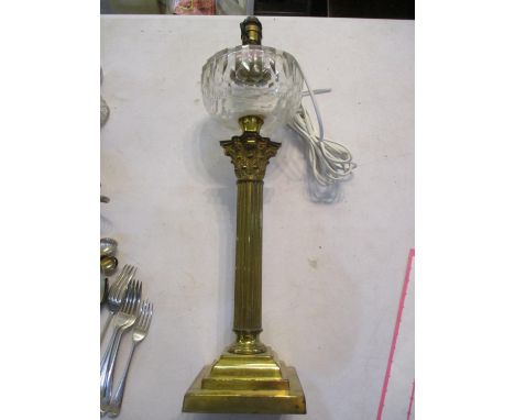 A brass table lamp having a Corinthian column and a glass reservoir 