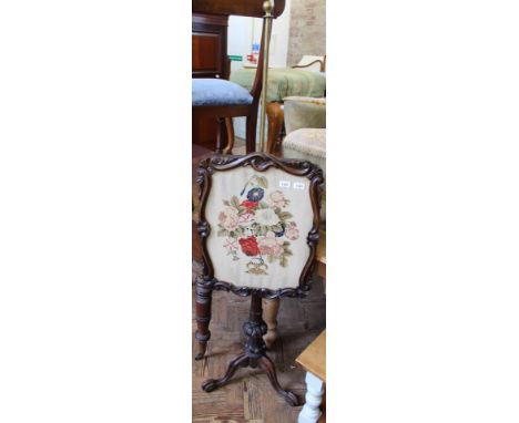 An ornately carved Victorian pole fire screen with floral tapestry 