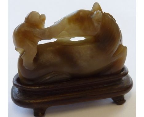 A Chinese Jade Carving of a Horse (Ma) with a small Monkey climbing upon its back, the Horse recumbent and with head turned t