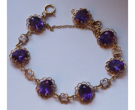 A ladies 9-carat yellow gold Bracelet and safety chain, the Bracelet set with seven hand-cut oval amethysts within pierced mo