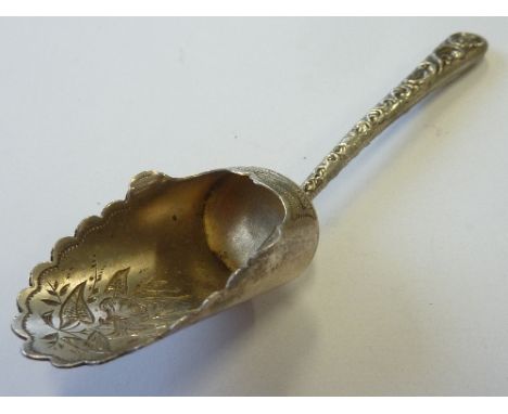 An ornate hallmarked silver Caddy Spoon the leaf- shaped bowl with serrated edge and engraved in bright cut style, the handle