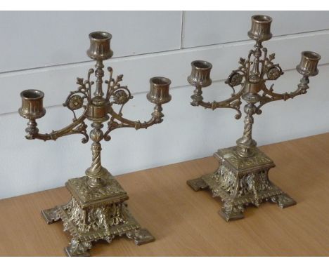 ADDED LOT    A pair of late 19th century Renaissance style three-light brass Candlesticks on square bases, 30cm high 