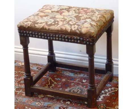 An 18th Century oak Stool having a later upholstered tapestry seat decorated with various fruits etc., raised on turned gun b