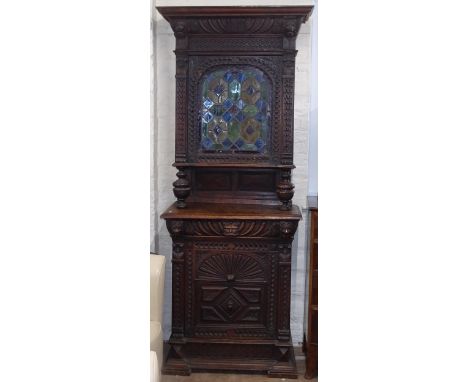 An ornate carved Belgian oak 2-section buffet, with a lead-light glazed coloured door, and allover relief carved and lion mas