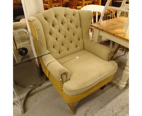 A button-back upholstered wingback armchair, on lined cabriole legs 