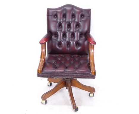 A studded and button-back red leather upholstered swivel desk chair 