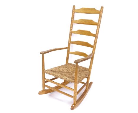 A mid-century Arts and Crafts Cotswold School style ladder-back rocking chair, in ash, with rush seat 