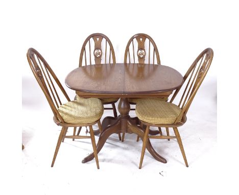 An Ercol oval extending dining table, together with a set of 4 matching swan-back dining chairs 